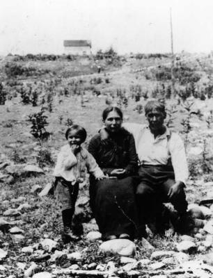 Photograph of a man, woman and a young boy sitting outside