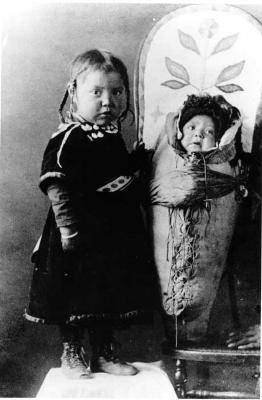 Photograph of two young children, one on a tikinagan