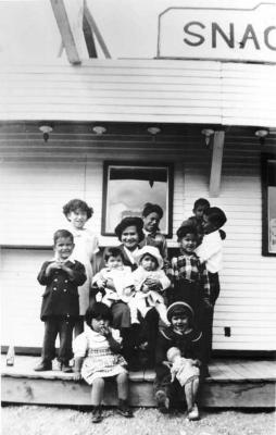 Photograph of a family sitting outside in front of a store