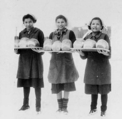 Photograph of three girls displaying loaves of bread