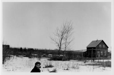 Photograph of a man, field and a house in winter