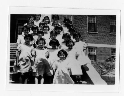 Group photograph of junior girls on the front steps of Shingwauk Hall